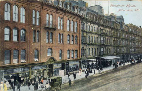 Elevated view across street toward the hotel which has an awning over the entrance to the sidewalk, which is crowded with many pedestrians. Several horse-drawn carriages are in the road. Caption reads: "Plankinton House, Milwaukee, Wis."