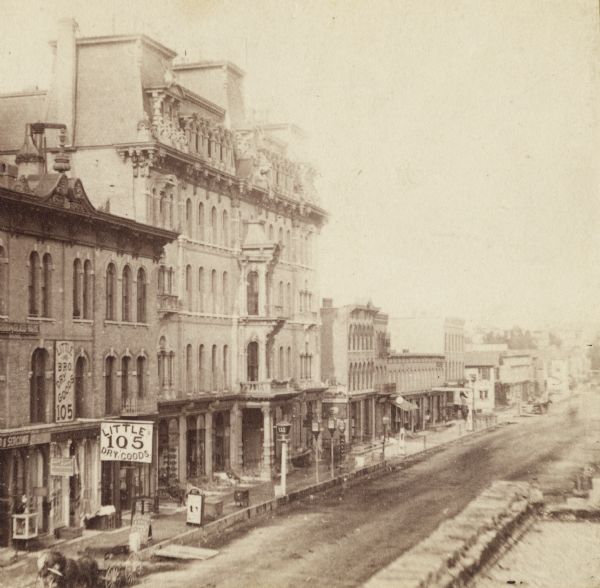 Stereograph. The Plankinton House is in the near foreground across the street. A sign for Little Dry Goods, 105, is on the left, above a horse-drawn cart.
