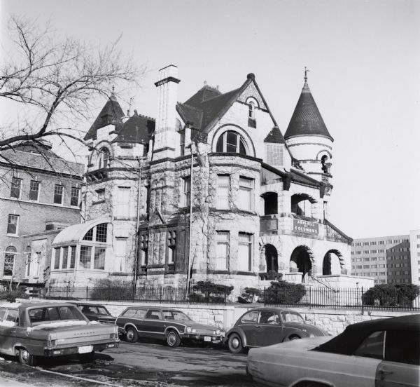 1492 W. Wisconsin Avenue. Built in 1886 by John Plankinton for his daughter Elizabeth. Edward T. Mix was the architect.  Listed in the National Register of Historic Places 1976. A lighted sign for the Knights of Columbus is above the main entrance on the right. Several cars line the road, and a brick and metal fence separate the house from the street.