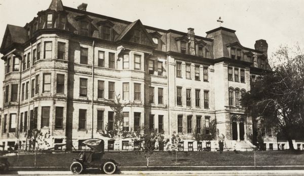 A section of the building at the right was erected in 1859; the section at the left is of later construction.  The building was torn down in 1911.  A car is parked in front.