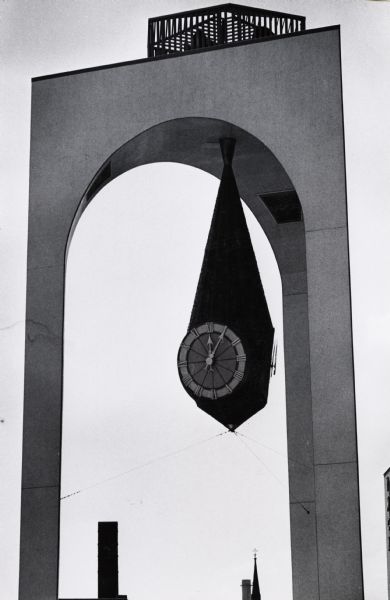 Close-up of the clock in the tower in the Milwaukee Civic Center Plaza.  The clock hangs from the inside roof of the three-legged tower in a teardrop-shaped section.