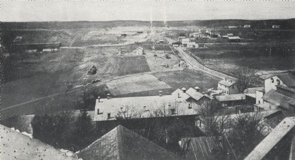 Elevated view from rooftops of what was known as Watertown Plank road, looking west from about North 35th Street. Several homes, and many open fields occupy the space.