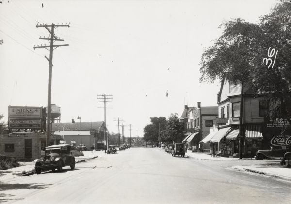 View down road of overhead lighting equipment of the T.M.E.R. and L. Company, which, at the time had a proposal to be replaced by more modern lighting.  The street light is suspended above the road.