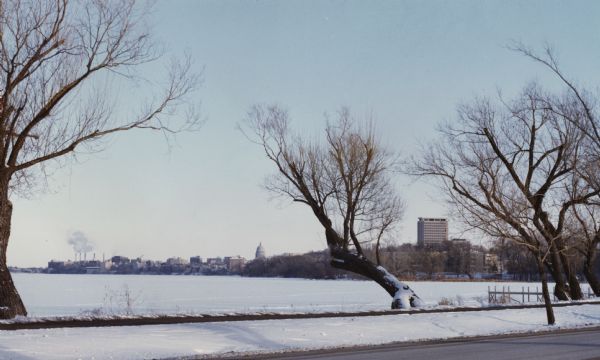 View of Lake Mendota and shoreline from University Bay Drive. Snow covers the lake and the shore.