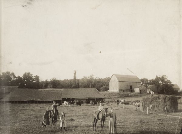 The manufacture of bricks was begun on this spot sometime in the latter 1860's by Henry Bretag, a German brickmaker, the father of Mrs. Englehardt.  Brick making discontinued in 1910 due to lack of proper clay.  From left to right: Elizabeth C. Englehardt, Gordon L. Keeley of Hudson on horse, Laura Englehardt, Guy Englehardt on horse, and Mrs. Charles Englehardt. Charles Englehardt is standing on top of load of hay. Other men are farmhands.