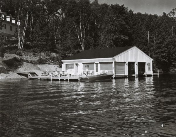 Wet boathouse that belonged to Don Walkins, on Catfish Lake. A woman stands on a pier near a boat.