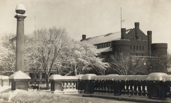 View from the terrace of the Wisconsin State Historical Society.  Snow covers the area, and a horse pulling a sled is in the lower left on Langdon Street. The Armory (Red Gym or Old Red) is in the background.