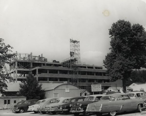 University of Wisconsin-Madison Bacteriology Building, in process of construction on campus. There are cars in a parking lot in the foreground.