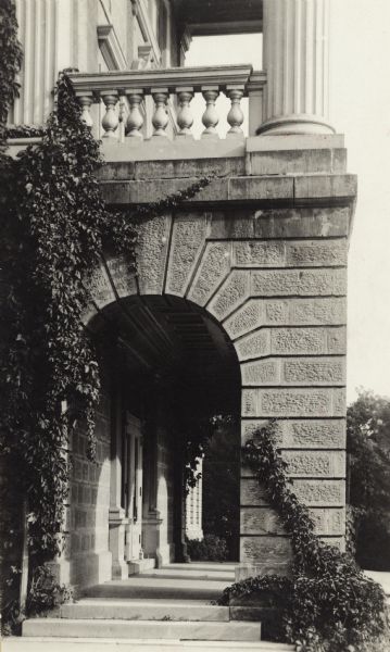 Exterior of side of front portico of Bascom Hall (formerly Main Hall) on the University of Wisconsin-Madison campus. Vines cover one side of the arch which supports a porch with large columns over the main entrance to the building.