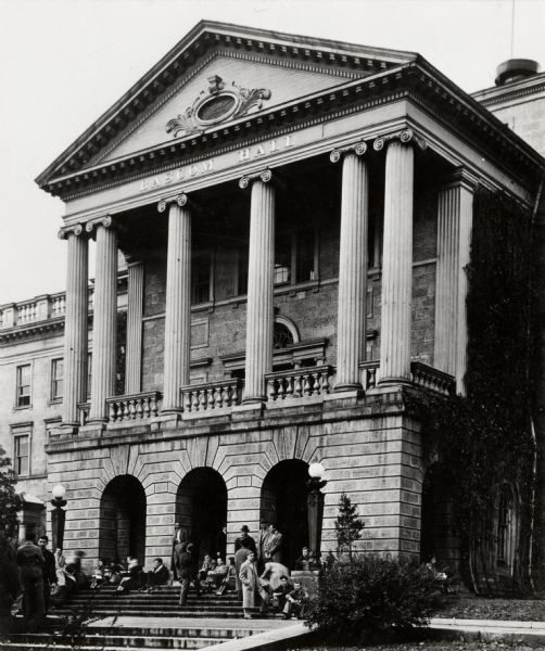 A group of people are gathered on the stairs in front of the main entrance of Bascom Hall (formerly Main Hall) on the University of Wisconsin-Madison campus.
