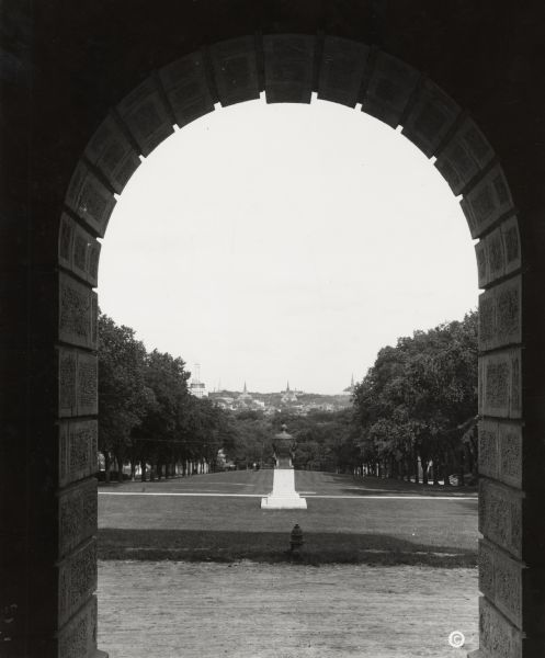 Lincoln Monument on Bascom Hill from arch of Bascom Hall (formerly Main Hall) on the University of Wisconsin-Madison campus.  The city of Madison is in the distance. At this time the Wisconsin State Capitol dome was under construction, which is just above the left tree line.