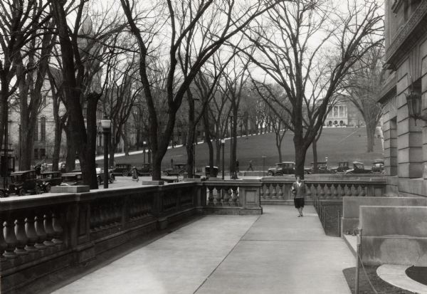 View along State Historical Society building up Bascom Hill on the University of Wisconsin-Madison campus. Automobiles are parked along Park and State Street. Bascom Hall (formerly Main Hall) can be seen at the top of the hill.