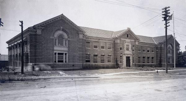 View across road of building on the University of Wisconsin-Madison campus. Built by the University of Wisconsin and operated by the United States Forest Services. Telephone and electric wires are in front of the building. A flag waves at the top of a pole on the right.