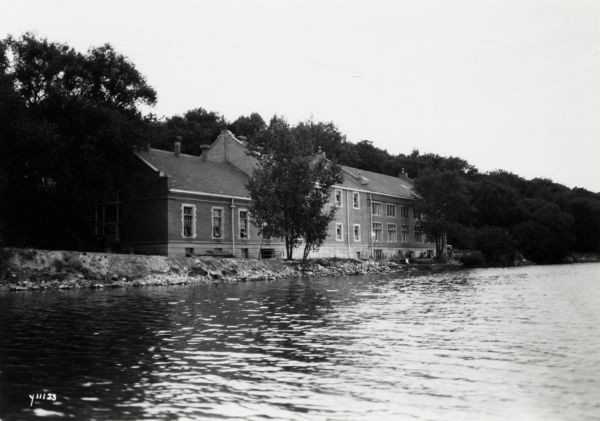 View from water of the Hydraulic Engineering Building on the University of Wisconsin-Madison campus. The building is located on the edge of Lake Mendota and is surrounded by trees.