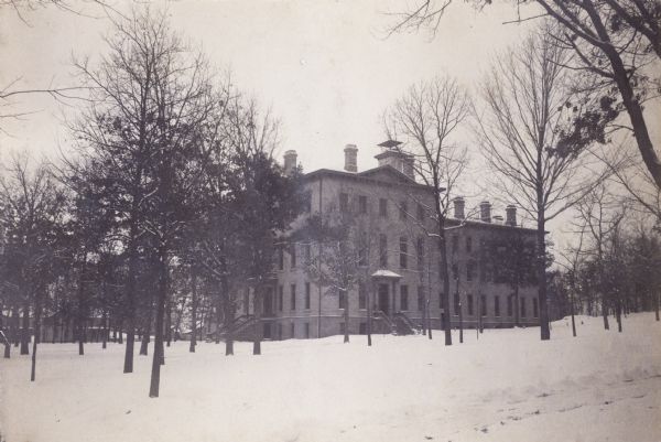 Exterior of University of Wisconsin-Madison women's dormitory, later Chadbourne Hall. The building is surrounded by trees and snow is on the ground.