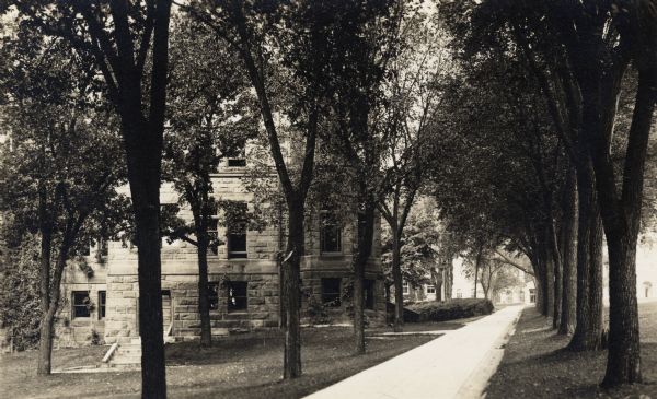 View up tree-lined path on Bascom Hill of building on the University of Wisconsin-Madison campus. Bascom Hall can be seen at the top of the hill on the right.