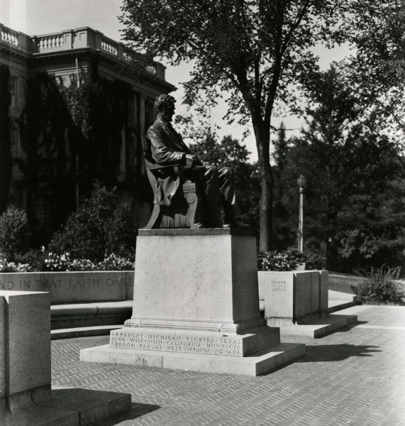 Lincoln Monument in front of Bascom Hall on the University of Wisconsin-Madison campus. A stone bench, plantings and walkway surround the back of the monument.