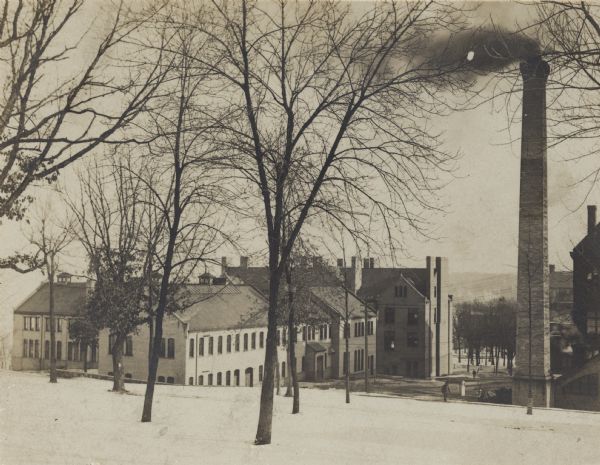 View down hill of Machine Shop, Electrical Laboratory and Industrial Arts Laboratory, on the University of Wisconsin-Madison campus. A large smokestack is on the right.
