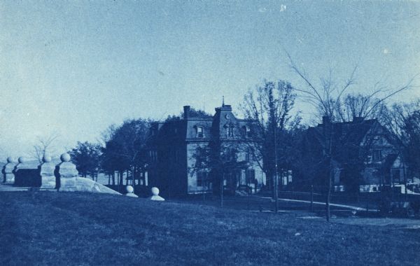 Cyanotype view of the residence on the University of Wisconsin-Madison campus. The president's home is at the corner of Langdon and Park Streets, the current location of Memorial Union. Lake Mendota is visible through the trees in the background, and the stairs to Science Hall are on the left.