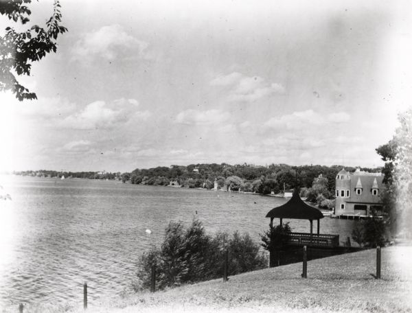 View from shoreline of Lake Mendota for the end of Park Street, including the boathouse (backyard of Olin House located at 766 Langdon Street) on the University of Wisconsin-Madison campus. In the foreground is a small pavilion with an ogee roof line.