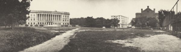 Panoramic view of University of Wisconsin-Madison campus, with the Wisconsin State Historical Library, old Y.M.C.A., and Armory (Red Gym or Old Red). The buildings surround an open area with worn walking paths. State Street is on the left side of the image, and a tall fence is on the right.