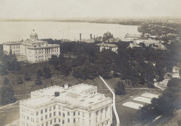 Elevated view looking northeast from the chimney of the Power Plant on University Avenue. The Chemistry Building is in the foreground, and Bascom Hall and Lake Mendota are in the background. Numerous other University of Wisconsin buildings including South Hall. Visible at right center may be the construction site of Lathrop Hall, completed in 1910.