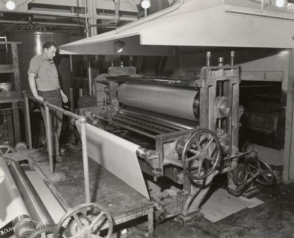 A Consolidated Paper Company employee watches the paper impregnation process whereby the company made a plastic laminate product used in the manufacture of military gliders during World War II.