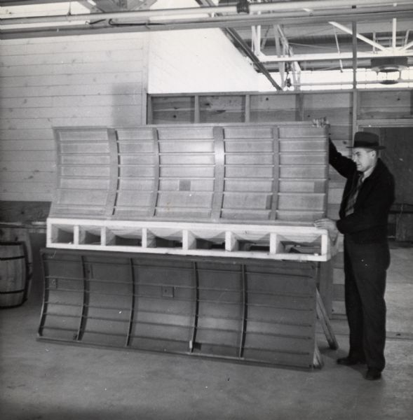 An employee of the Plastics Division of Consolidated Paper Company holds up a structure for it to be photographed.  The object is thought to be a prototype of the lightweight gliders manufactured by the company during World War II. 