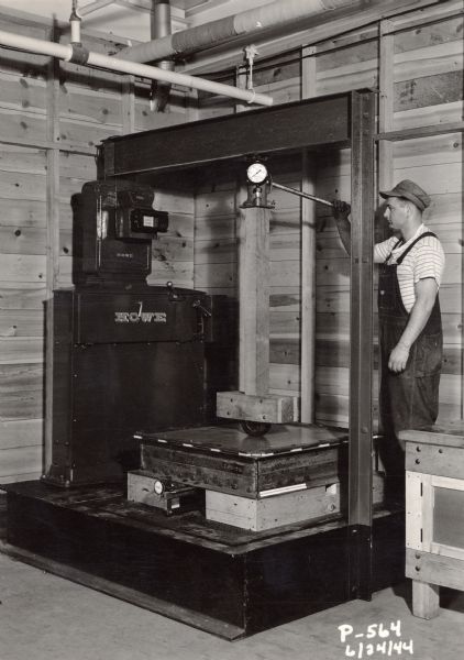 Strength test being performed by an employee of the Plastics Division of the Consolidated Paper Company.  The company developed a number of laminated plastic products for use by the military in the war effort.