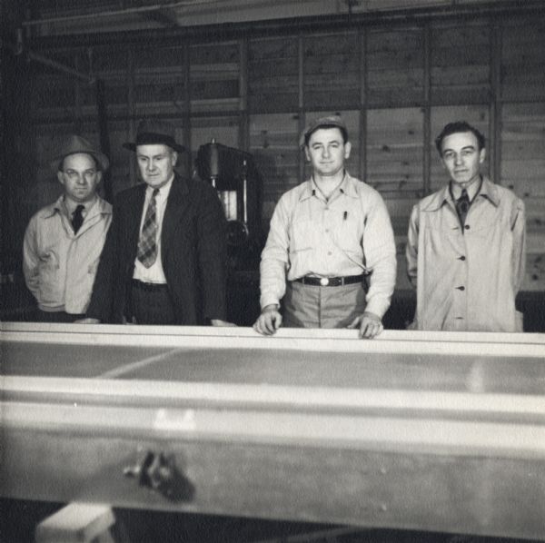 Four employees of the Plastics Division of Consolidated Paper Company with the first glider floor manufactured by the company for the military during World War II. The employees are Frank Novak, Carl Husome, Irv Bogs, and Larry Crunelle.
