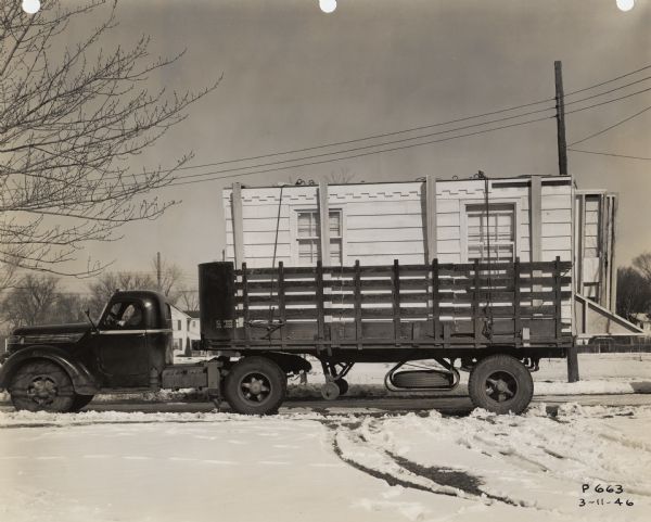 A truck arrives at a construction site in Wisconsin Rapids loaded with walls for a factory-built house.  The house was the product of the Plastics Division of Consolidated Papers, Inc., and it was developed to meet the need for inexpensive housing after World War II.