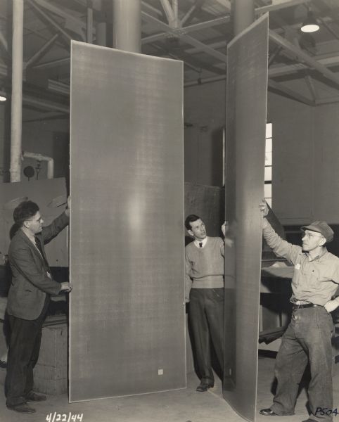 Three employees of the Plastics Division of the Consolidated Paper Company pose with two sheets of the paper-based plastic laminate that the company manufactured for various products during World War II.