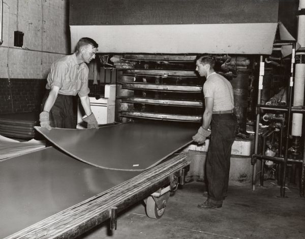 Bill Hardina and Tony Kissner, two employees of the Plastic Division of Consolidated Papers of Wisconsin Rapids, handling large sheets of the paper-based plastic laminate manufactured by the company.