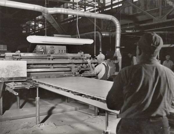 Employees of the Plastics Division of the Consolidated Papers Company of Wisconsin Rapids and a large sheet of the paper-based plastic laminate manufactured by the company.