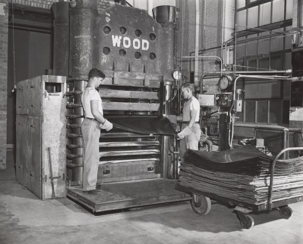 Workers at the Plastics Division of the Consolidated Papers Company of Wisconsin Rapids handling sheets of the paper-based plastic laminate manufactured by the company.