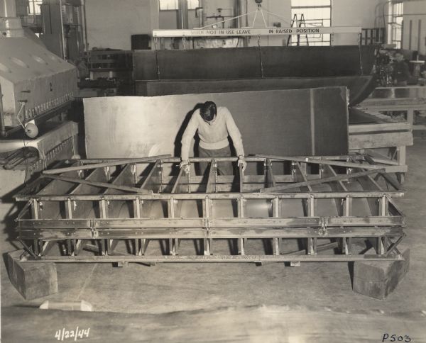 Employee of the Plastics Division of Consolidated Papers Company of Wisconsin Rapids contemplates a die for fabricating tapered paper-based plastic laminate for military purposes.