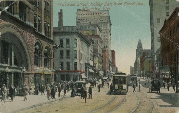 View of pedestrians and streetcar along Wisconsin Street. Caption reads: "Wisconsin Street, looking East from Grand Ave. Milwaukee, Wis."