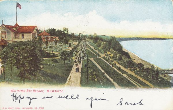 Elevated view of people walking on a path by the Whitefish Bay Resort along the lake front. Caption reads: "Whitefish Bay Resort, Milwaukee."