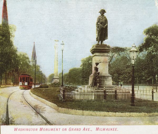 Washington Monument on Grand Avenue with a streetcar coming up the street in the background. Caption reads: "Washington Monument on Grand Ave., Milwaukee."