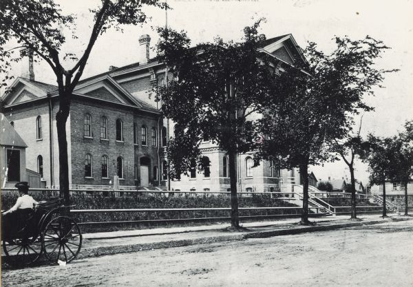 Exterior of Walter Allen School, with a woman in a carriage parked in front. The Walter Allen School was an elementary school located at 1657 South Third Street. In 1949 the school was still in use and was the oldest school building in Milwaukee.