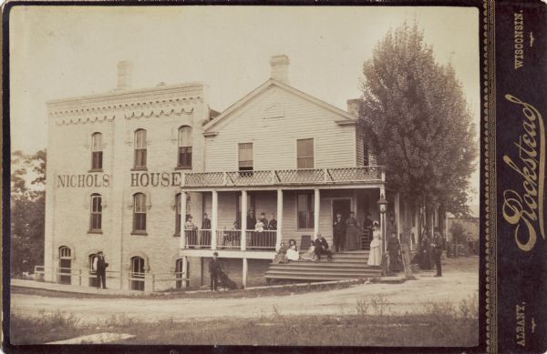Group of people posed on and around porch of the Nichols House.