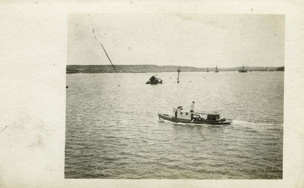 Elevated view of a tugboat, with possibly a sinking ship in the background.