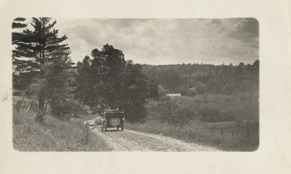 The Milwaukee Journal Pathfinder traveling down a dirt road in the country.