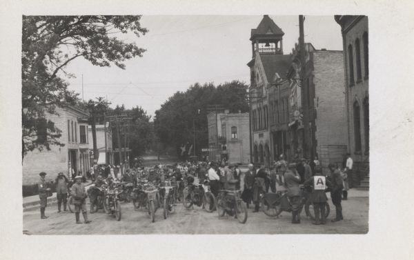 A large group of motorcycles and riders are gathered in the middle of a city street.