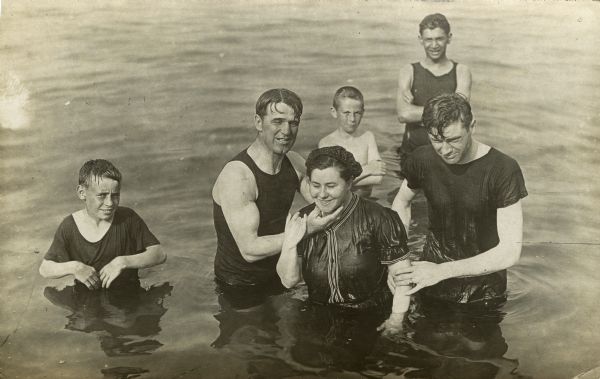 Group portrait of a small group of men, women, and children standing waist-deep in the water.