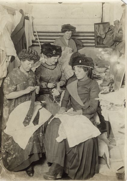 A group of four women sewing in a business setting.