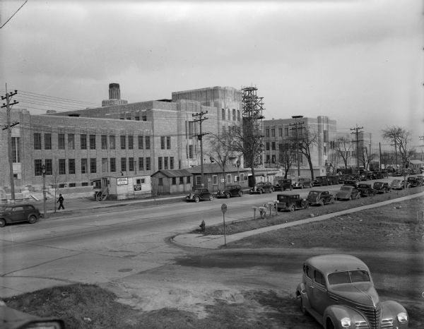 Exterior view of the Kroening Engineering factory. Cars are parked along the street outside the building.
