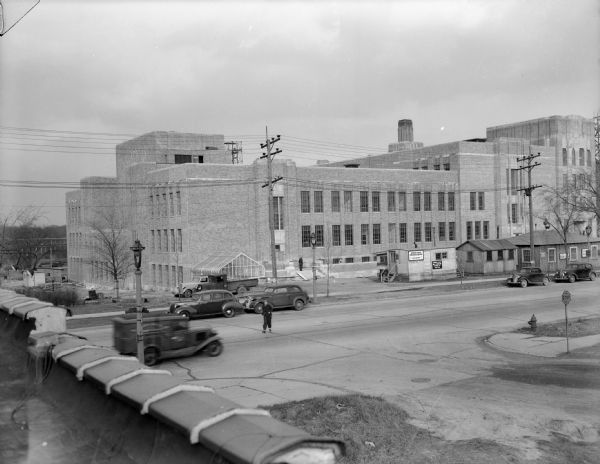 Exterior view from a roof of the Kroening Engineering factory. Cars are parked along the street outside the building.