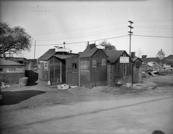 A fish shop made of several small, interconnected buildings.  Signs for fresh or smoked fish are on several parts of the shop. In the background is a railroad car.