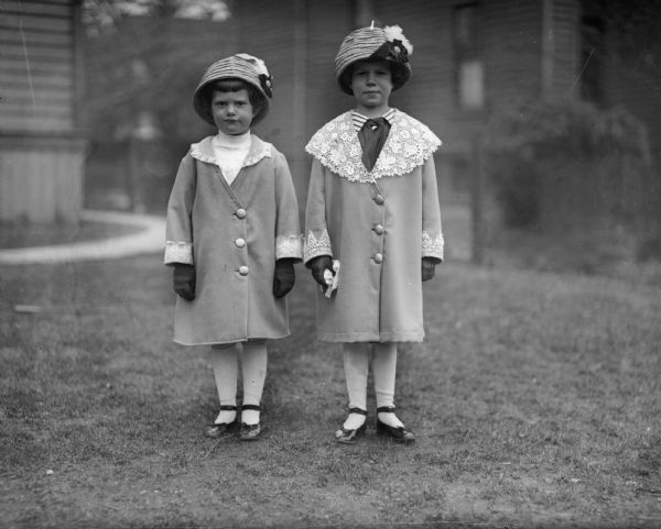 Outdoor portrait of Donna and Ellen Taylor posing in matching gloves, hats and coats.